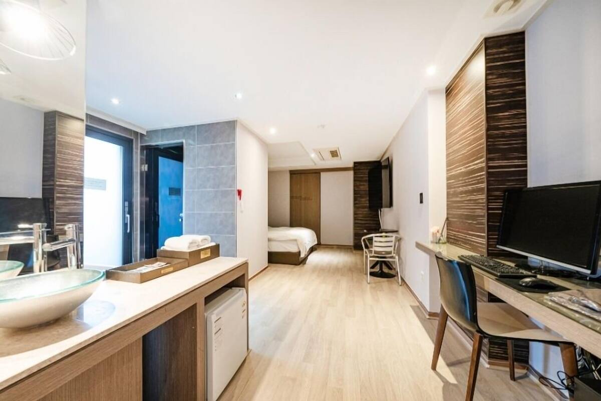 A modern hotel room with a large bathroom, a dining area, and a TV.
