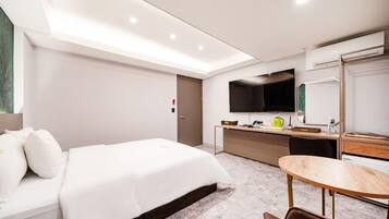 Una habitación de hotel moderna con una cama grande, un escritorio, una silla, un televisor de pantalla plana y un espejo.