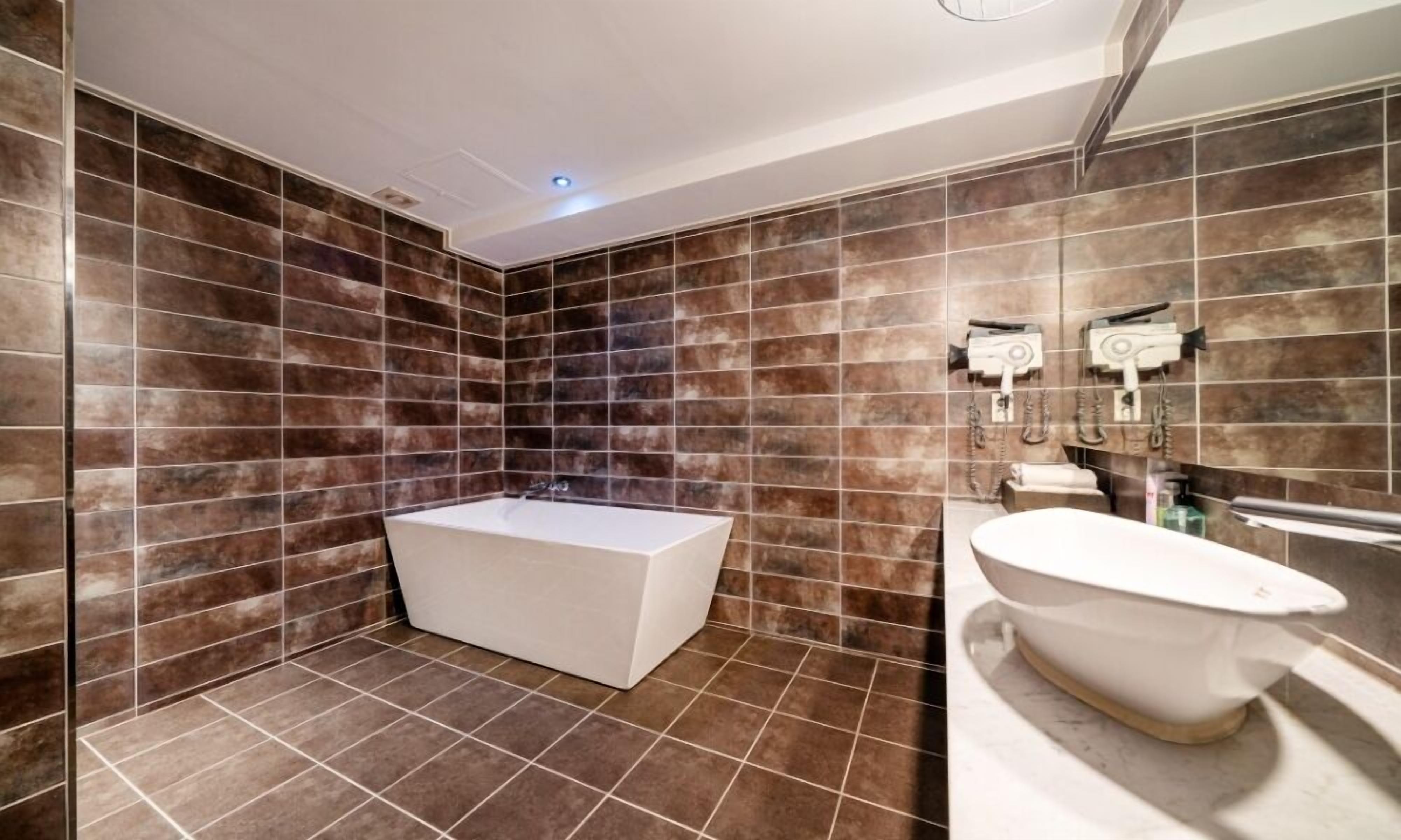 A modern bathroom with a bathtub, a freestanding sink, and a large mirror.