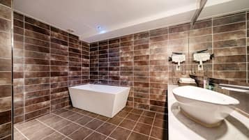A modern bathroom with a bathtub, a freestanding sink, and a large mirror.