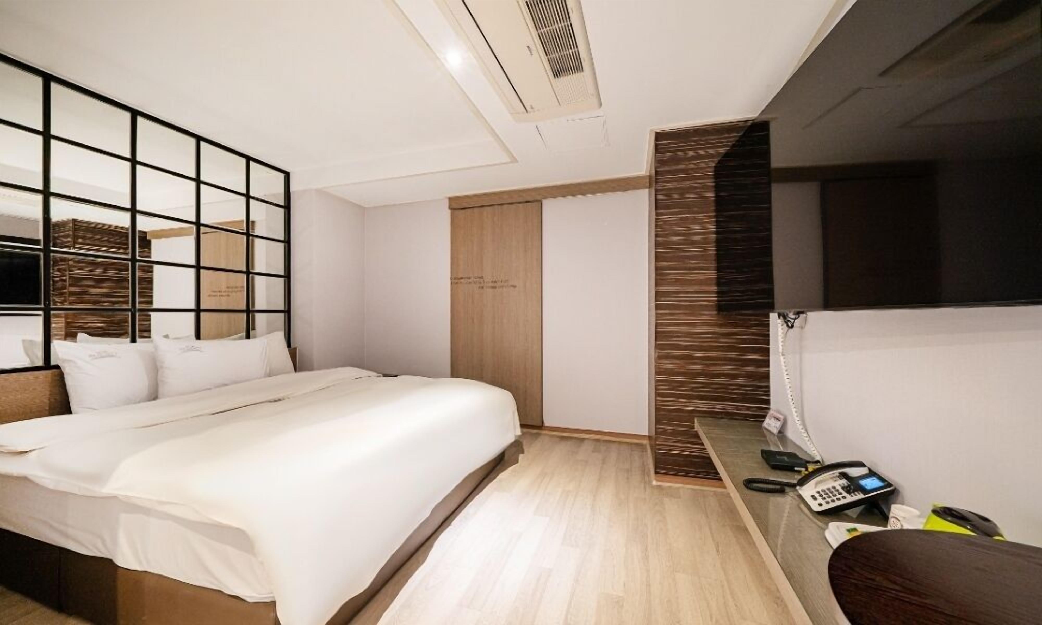 A hotel room with a bed, a desk with a telephone, and a wardrobe.