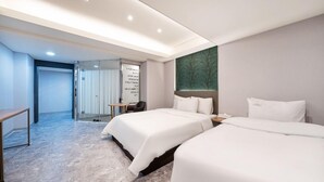 Quarto de hotel com duas camas, uma mesa de escritório e uma área de estar.