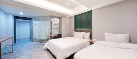 Habitación de hotel con dos camas, un escritorio y una zona de estar.