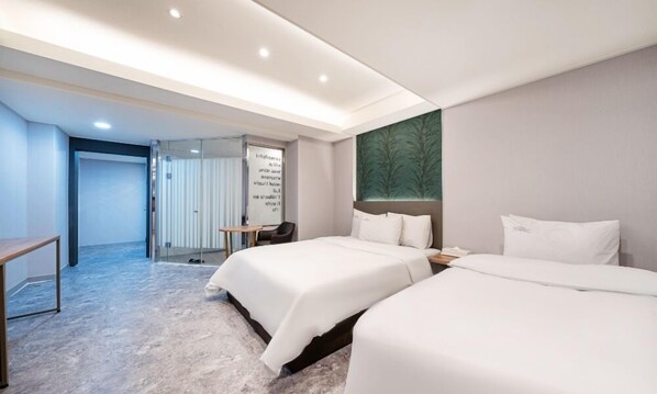 A hotel room with two beds, a desk, and a seating area.