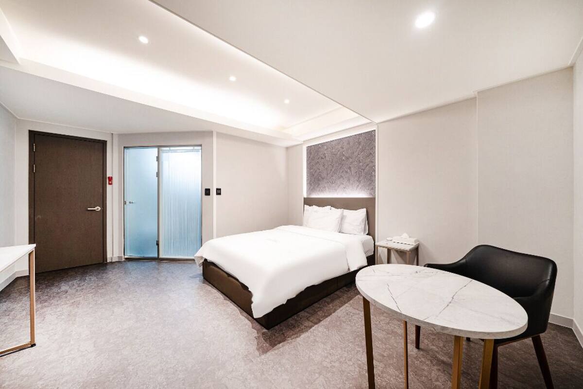 A modern hotel room with a large bed, a small table, and a chair.