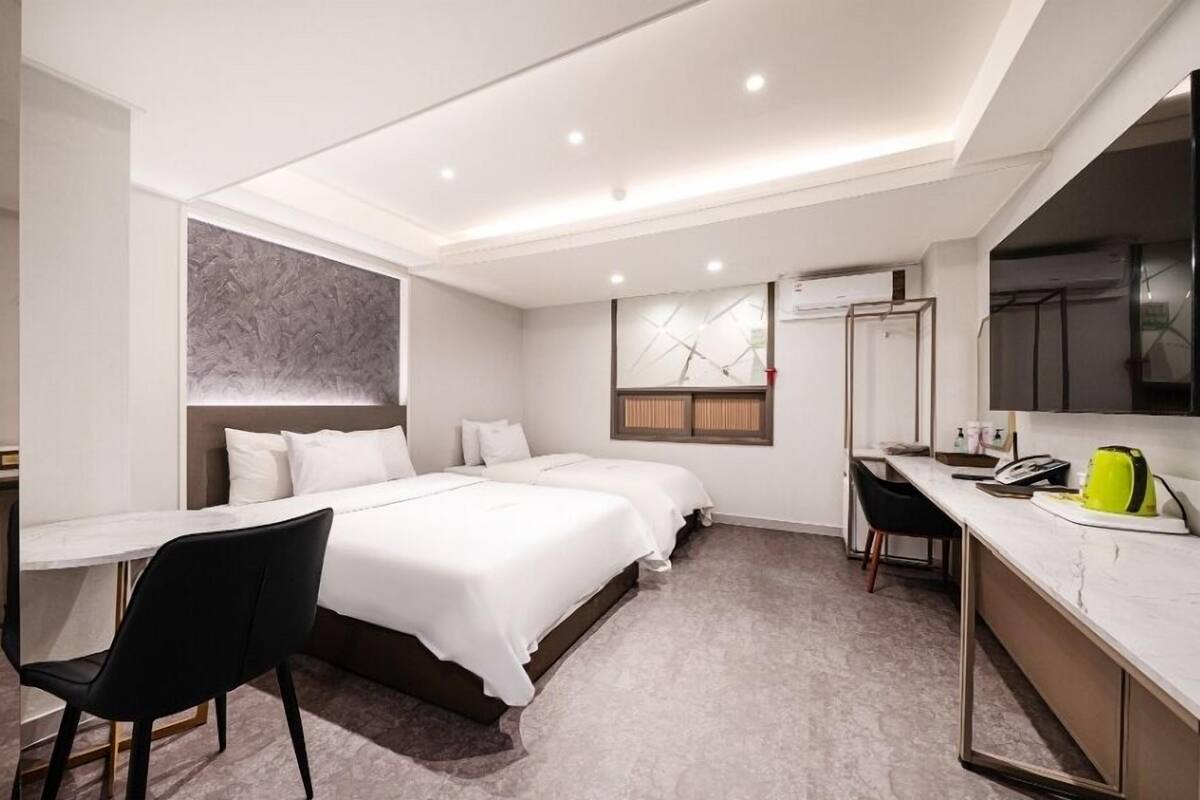 A hotel room with a bed, a desk, a chair, and a large mirror.