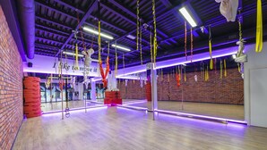 A spacious room with hanging aerial yoga equipment, a brick wall, and a mirrored wall. - Hotel Scout (Czestochowa)