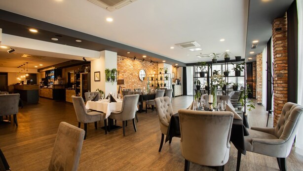 A modern restaurant with a brick wall, wooden flooring, and a variety of seating arrangements including tables and chairs. - Hotel Scout (Czestochowa)