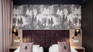 A hotel room with two beds, a dark headboard, and a forest-themed wall mural. - Hotel Scout (Czestochowa)