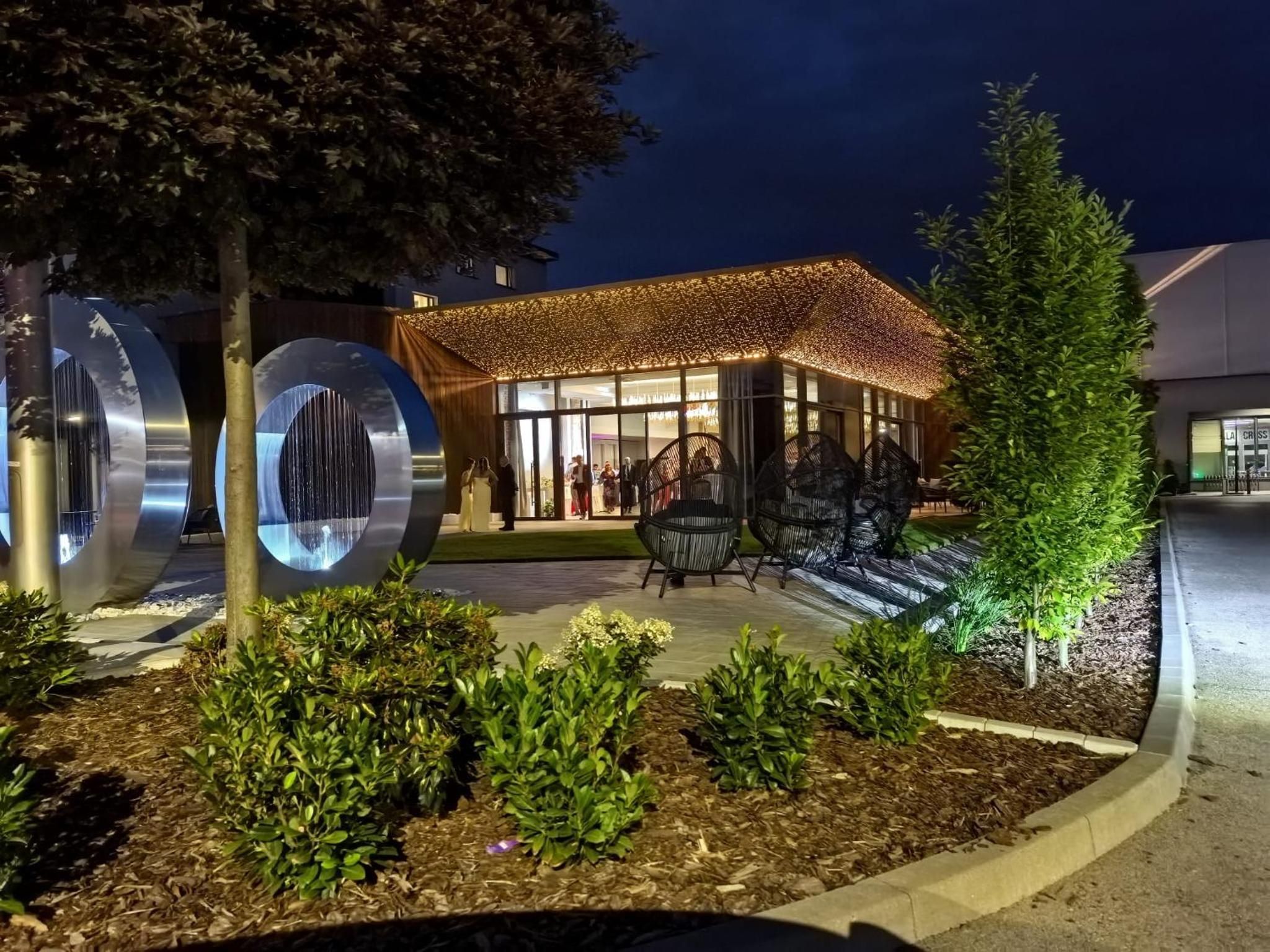 A building with a modern design, featuring a large metallic sculpture and a well-lit entrance area.