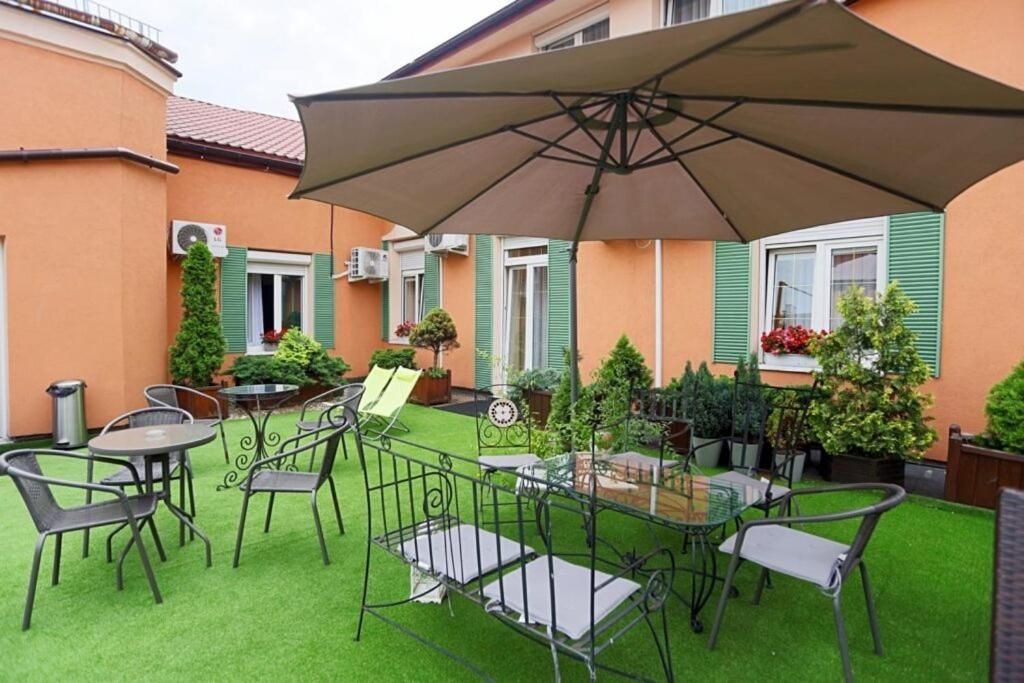 An outdoor patio with a table and chairs, surrounded by a green lawn and potted plants.