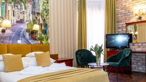 Een hotelkamer met een bed, een televisie, twee stoelen, een tafeltje en uitzicht op een straat.