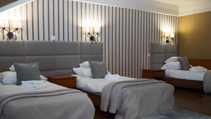 Habitación de hotel con dos camas, cada una con cabecera, mesitas de noche y lámparas.