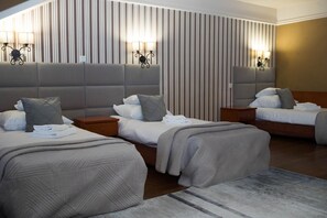 Habitación de hotel con dos camas, cada una con cabecera, mesitas de noche y lámparas.