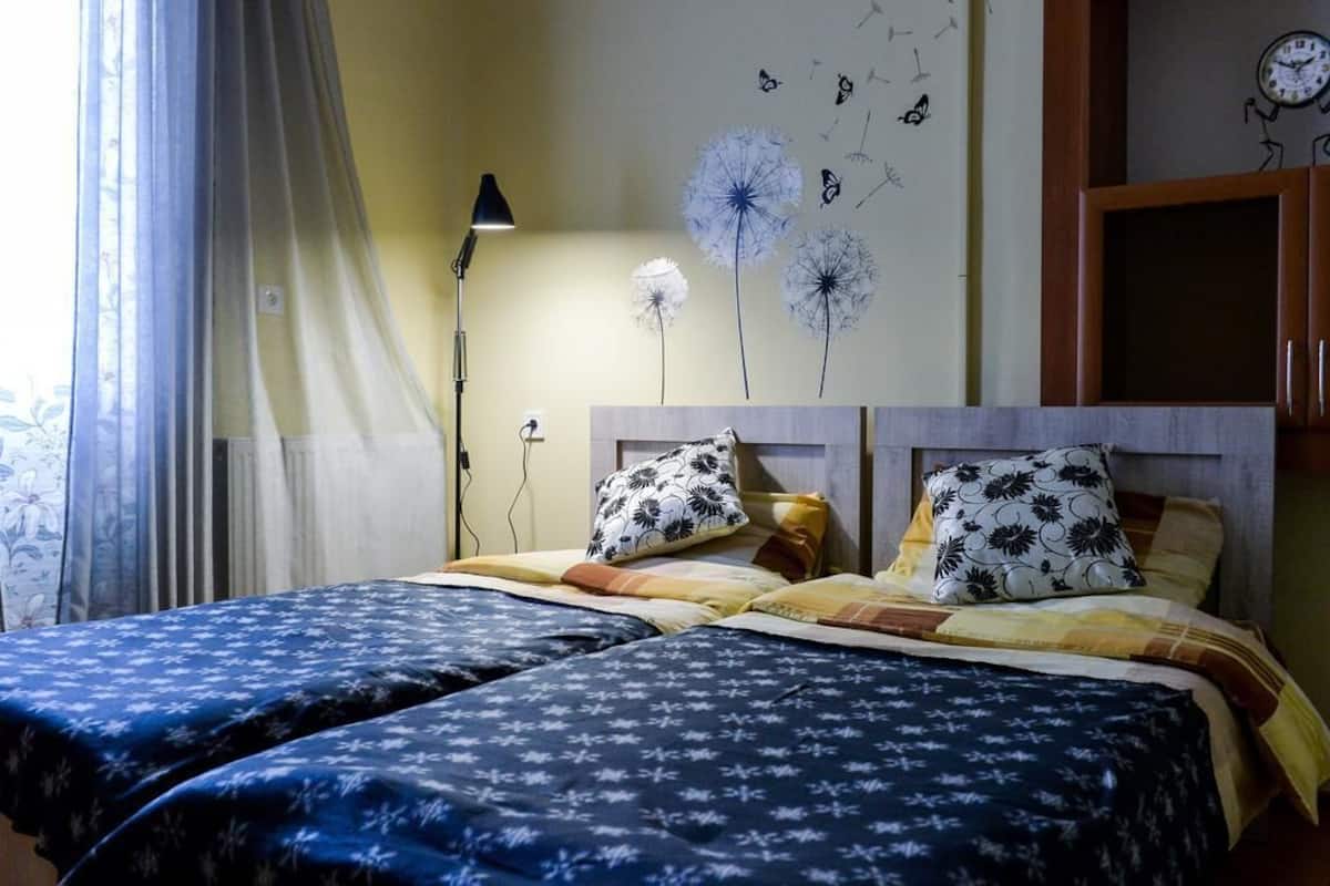 A double bed with floral-patterned bedding, a bedside lamp, and a wall clock.