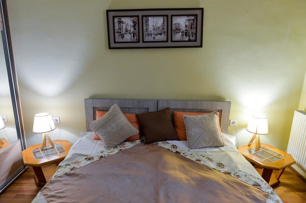 A neatly arranged hotel room with a bed, two bedside tables with lamps, a headboard, and three framed pictures on the wall.
