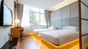 A hotel room with a bed, bedside tables, a TV, and a window with curtains. - Jianchuan Hotel (Jianchuan)