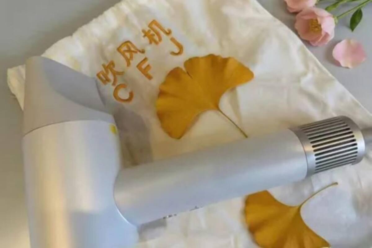 A white towel with yellow ginkgo leaves and Chinese characters, a white hairdryer, and pink flowers.