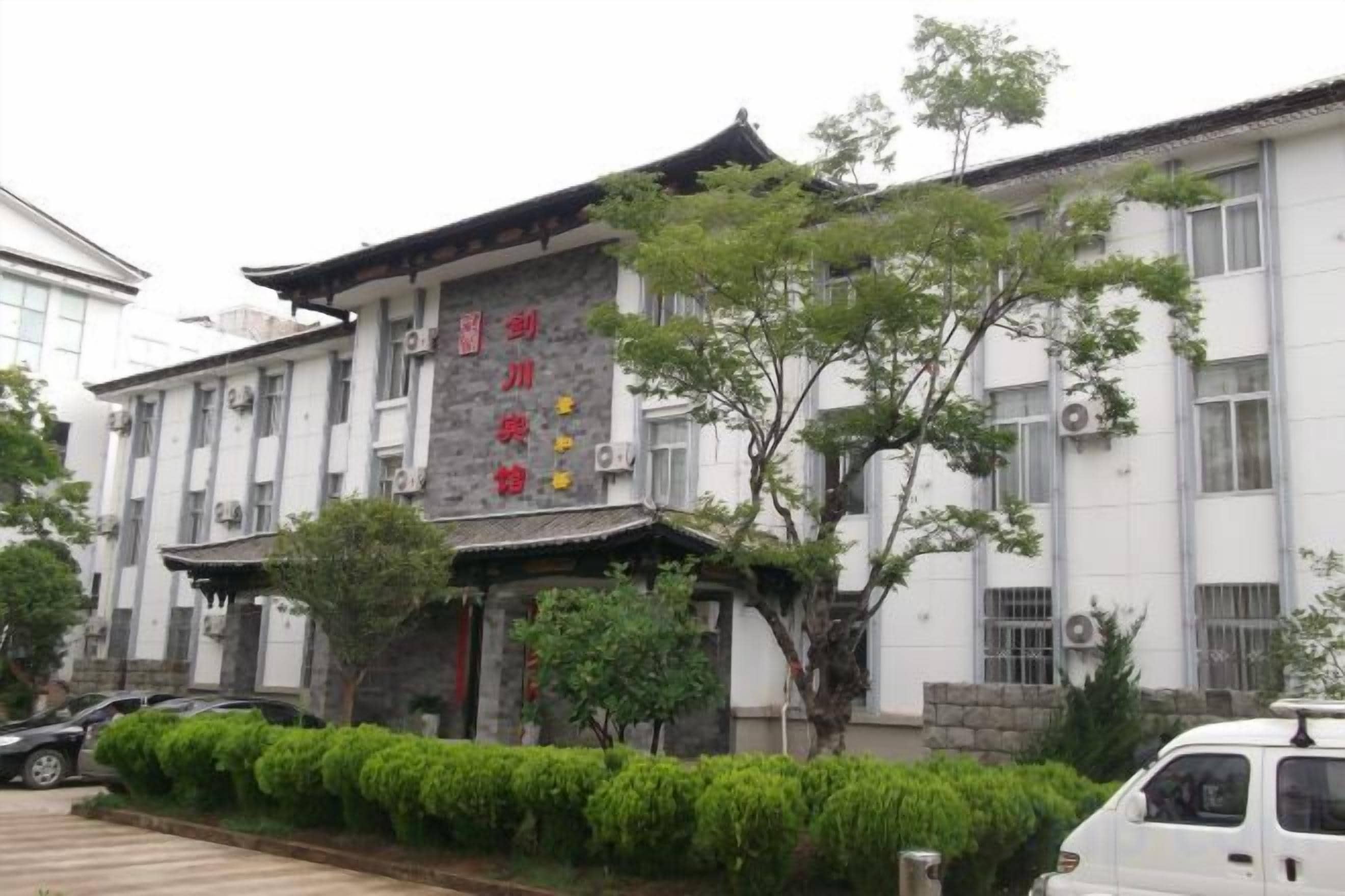 Edifício tradicional com placa, área de estacionamento e um veículo.