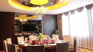 A dining area with a round table, chairs, a chandelier, and a large window with curtains. - Jianchuan Hotel (Jianchuan)