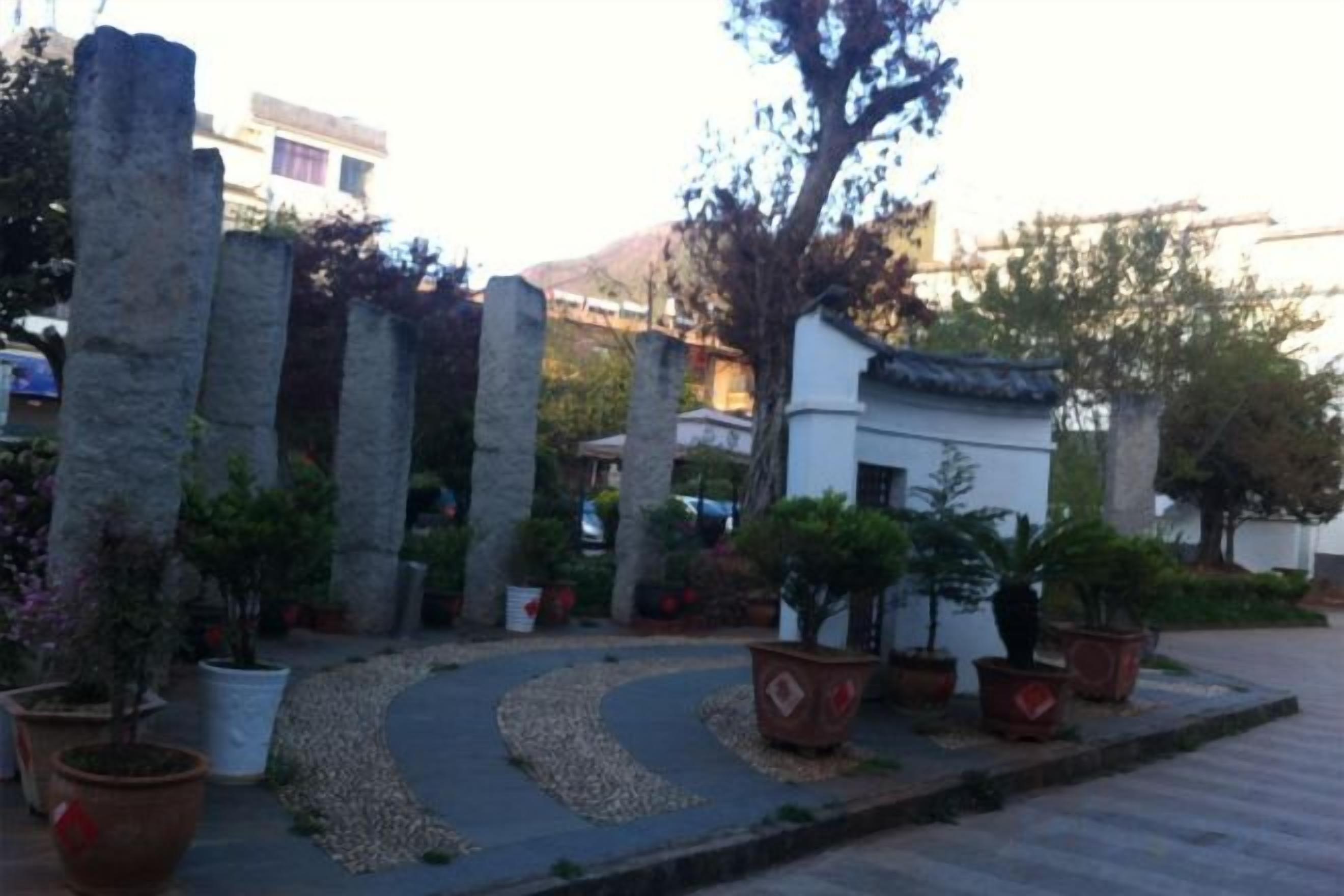 A courtyard with stone pillars, potted plants, and a pathway.