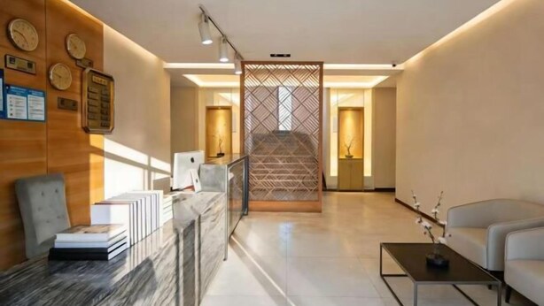 A modern hotel lobby with a reception desk, seating area, and a staircase. - Jianchuan Hotel (Jianchuan)