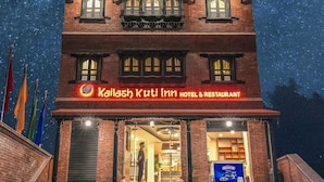 Ein Hotel mit einem Schild, auf dem ‚Kailash Kuti Inn Hotel & Restaurant‘ steht, unter einem sternenübersäten Nachthimmel.