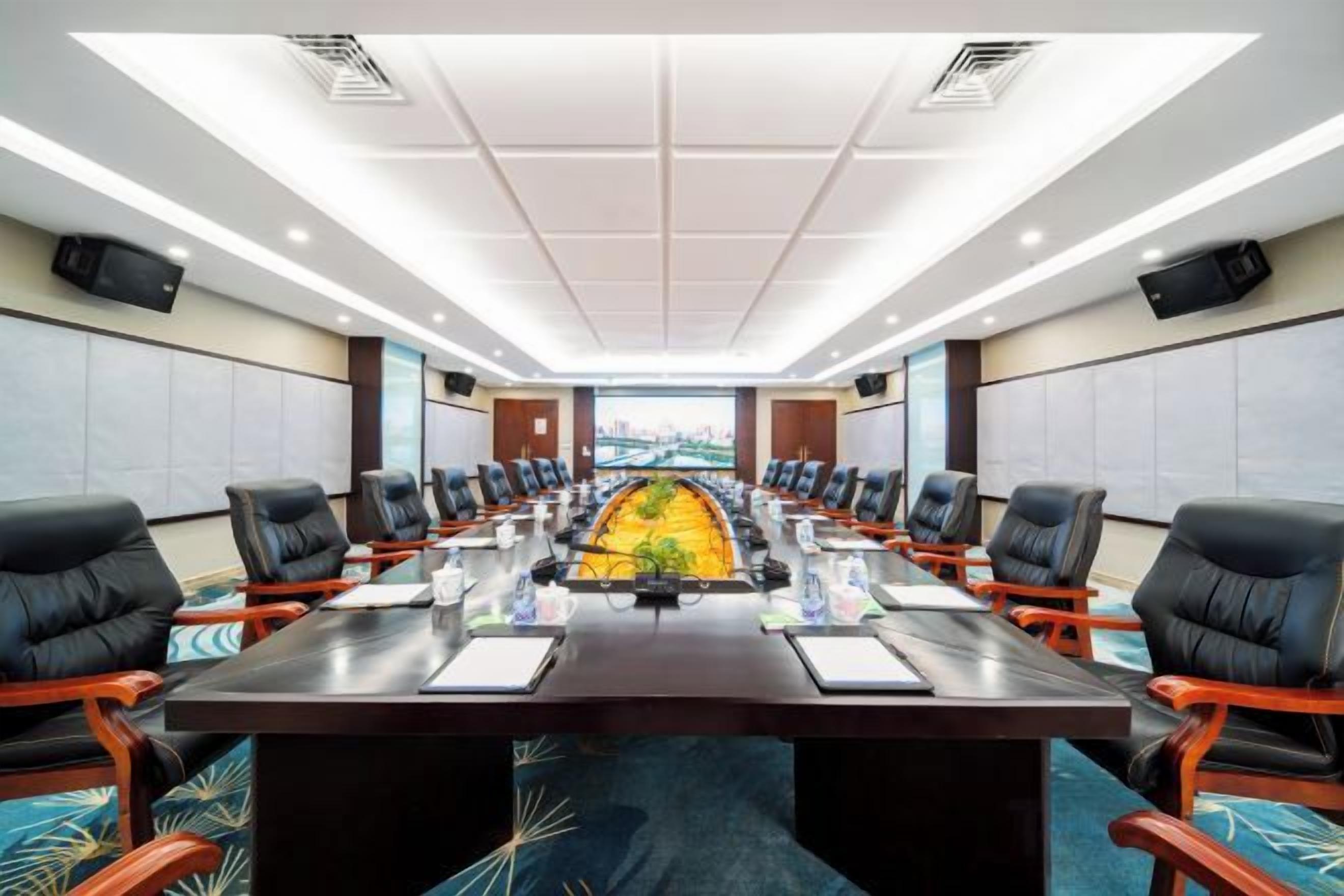 A conference room with a long table, multiple chairs, and a view through the windows.