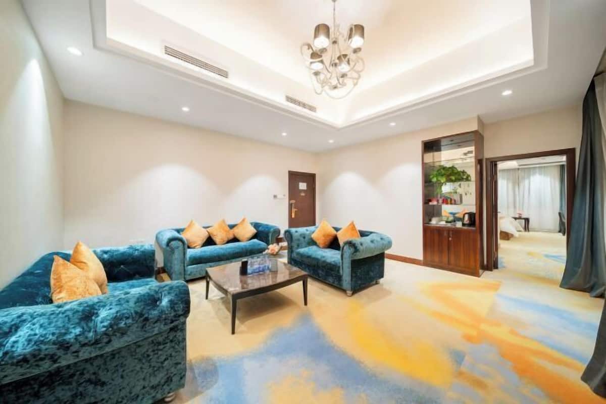 A spacious living area with a sofa set, a coffee table, and a chandelier.