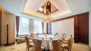 A conference room with a round table, eight chairs, and a chandelier.