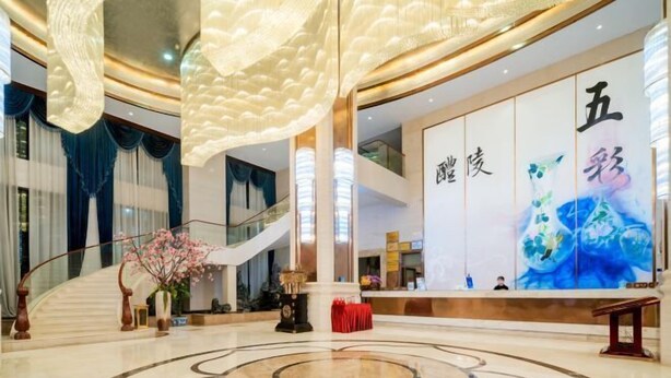 A spacious lobby with a grand staircase, a reception desk, and a large decorative wall.
