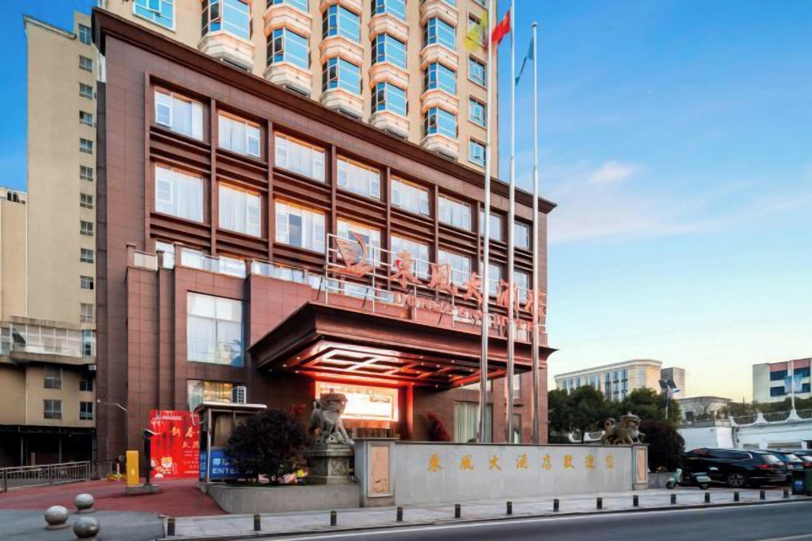 A multi-story hotel with a prominent entrance, a flag, and a statue in front.