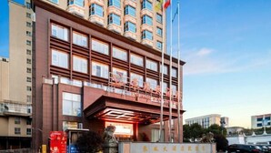 A modern hotel with a prominent entrance, multiple floors, and a clear sky.