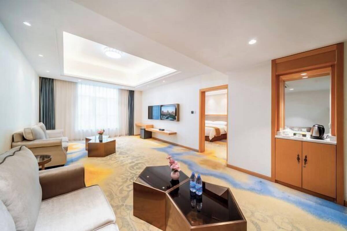 A hotel room with a sofa, a coffee table, a TV, a bed, and a wardrobe.