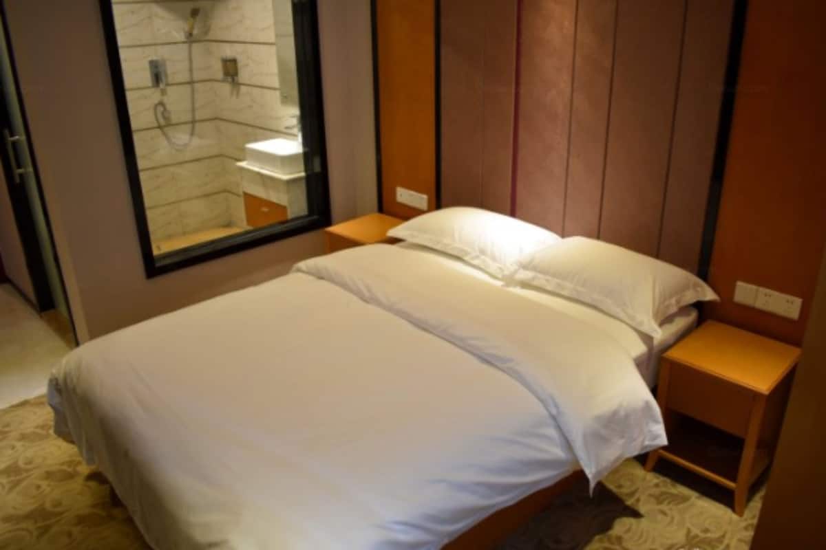 A neatly made bed with white linens in a hotel room.