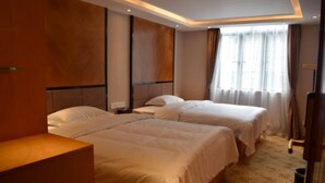 Habitación de hotel con dos camas, un escritorio y una ventana con cortinas.