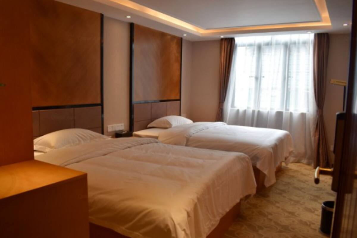 A hotel room with two beds, a desk, and a window with curtains.