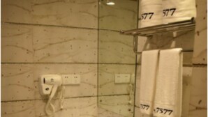 Un baño moderno con pared de mármol, un lavamanos blanco, un inodoro y una cabina de ducha con paredes de vidrio.
