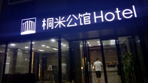 Entrada de hotel con un letrero que dice "柘米公馆Hotel" y una fachada moderna de vidrio.
