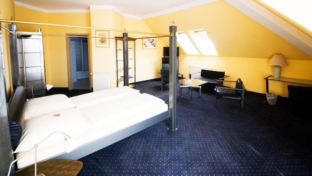 A hotel room with a bed, desk, chair, lamp, and skylight. - Hotel Mirage (Duisburg)