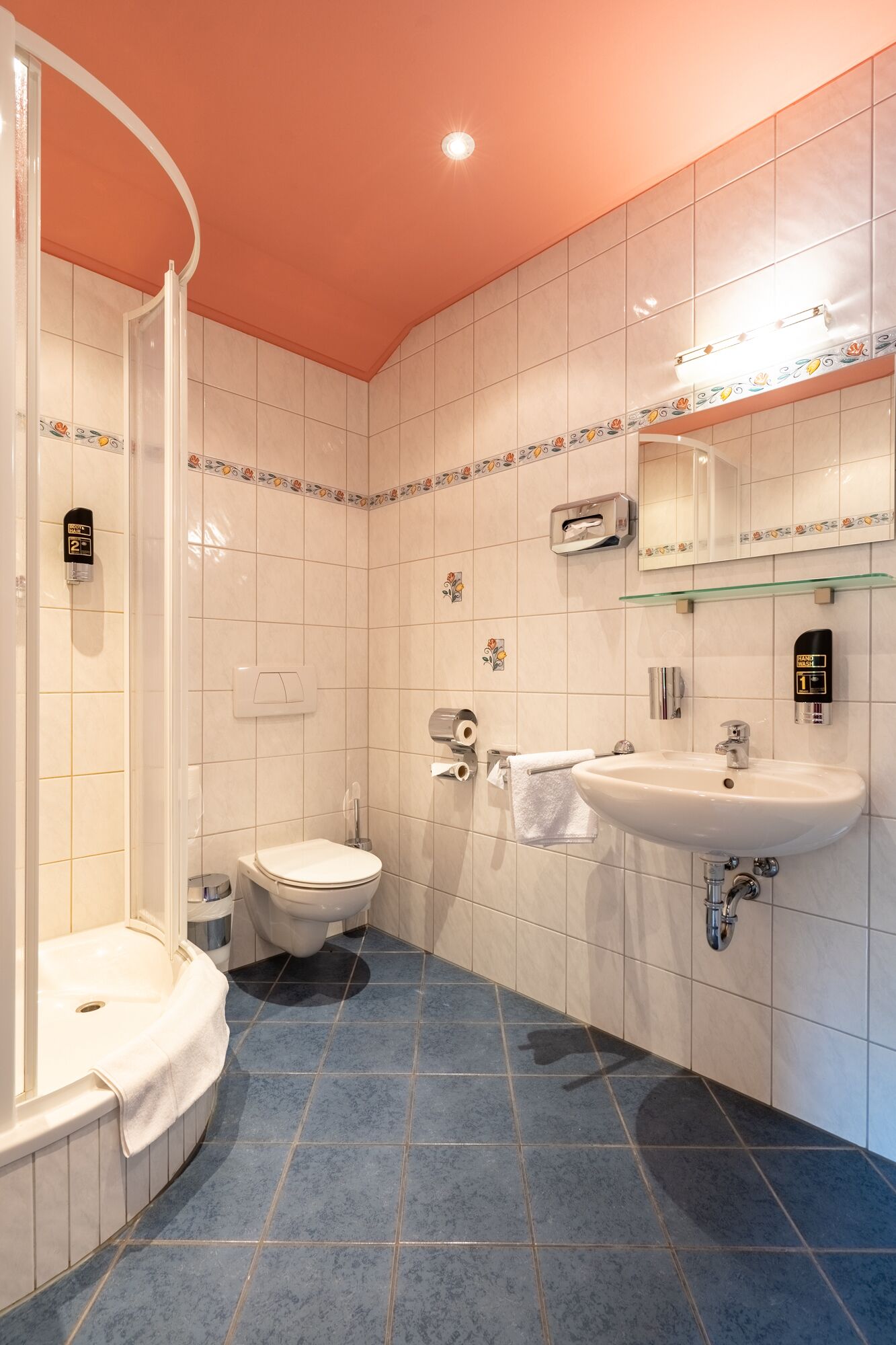 Un baño con ducha, inodoro, lavabo y un espejo con iluminación.