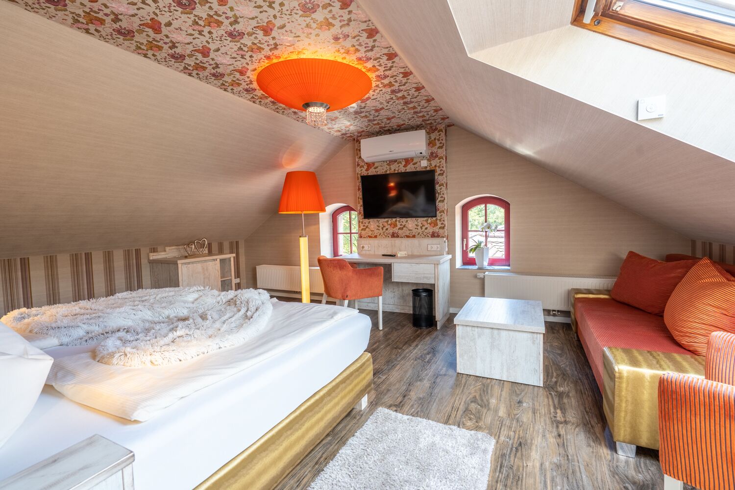 Een knus slaapkamer op zolder met een groot bed, een bureau en een bank.