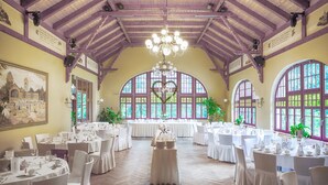A banquet hall with high ceilings, arched windows, and a chandelier. Tables are set for a formal event. - Berggasthof Butterberg (Bischofswerda)
