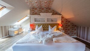 A bedroom with a large bed, a wooden headboard, a sloped ceiling, and a skylight. - Berggasthof Butterberg (Bischofswerda)