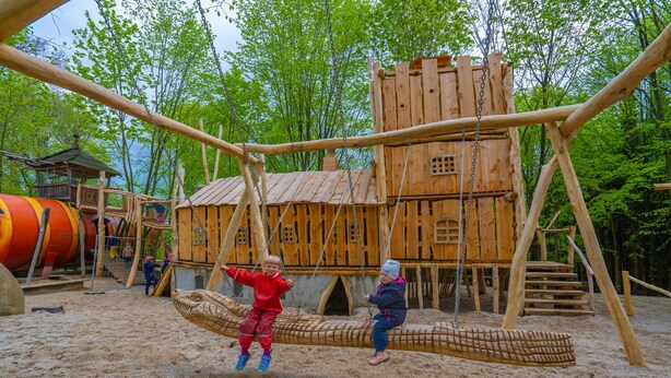 A playground with a wooden climbing structure and a swing set. - Berggasthof Butterberg (Bischofswerda)