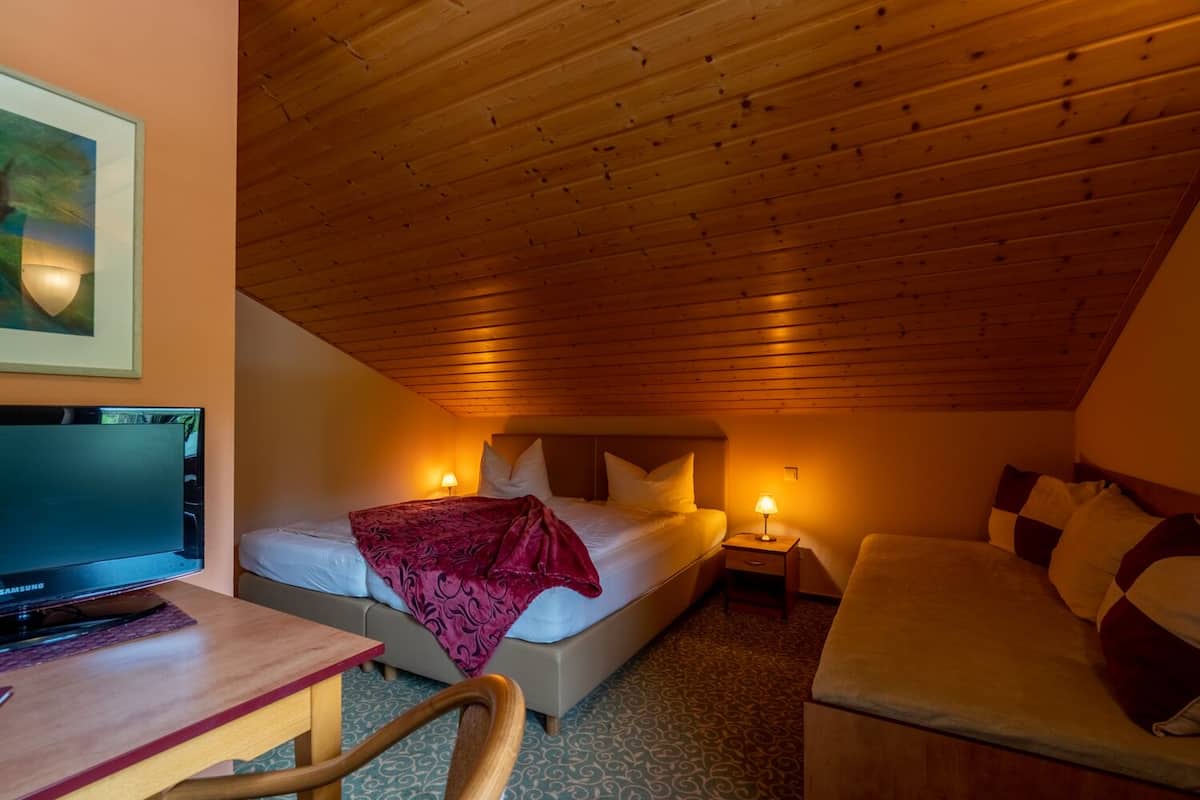 A cozy room with a bed, bedside tables, a desk, and a television.