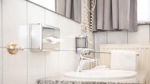 A bathroom with a sink, mirror, towel rack, and a towel hanging on the rack. - Hotel Lonac (Duisburg)