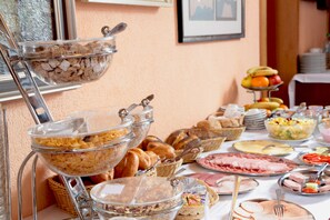 A buffet with various food items including bread, pastries, and meats.