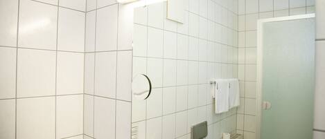 A bathroom with white tiles, a mirror, a towel rack, and a toilet.