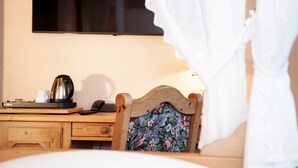 A hotel room with a wooden desk, a telephone, a kettle, and a floral-patterned chair. - Hotel Lonac (Duisburg)